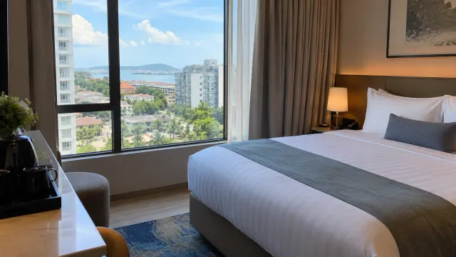 A neatly made guest room with a window view of a 4-star city hotel — Aglow Hotel Harbor Bay Batam, a 4-star city hotel in Harbour Bay, Batam