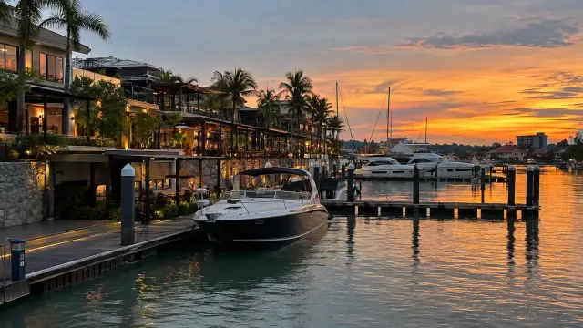 A marina strip of bars and restaurants with boats at the jetties at dusk — Waterfront City Marina, a marina bars in Sekupang, Batam